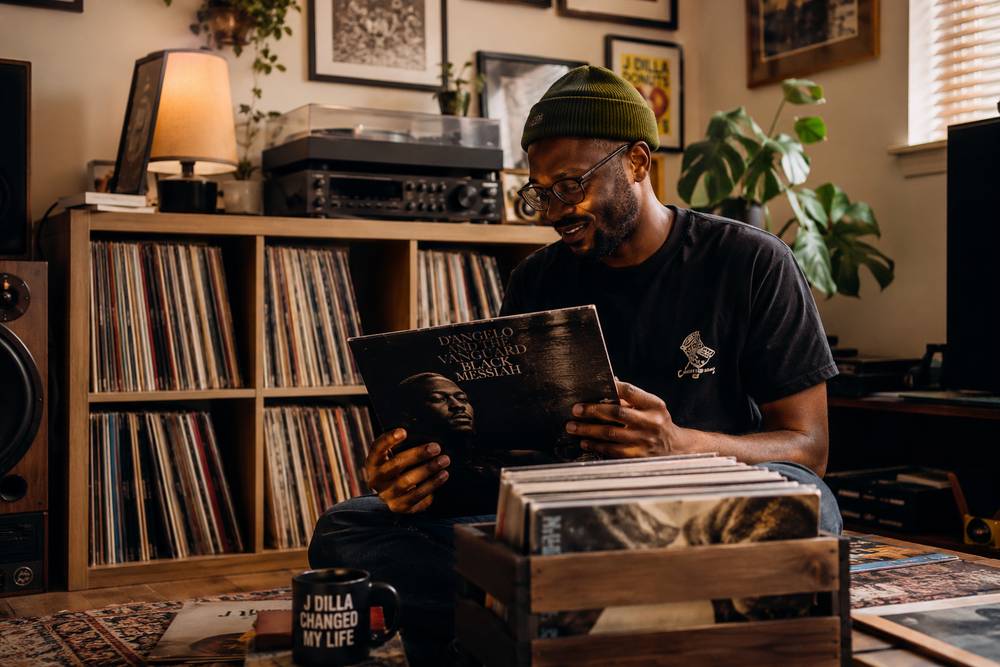 A collector reading the sleeve of a record in front of a wall of records
